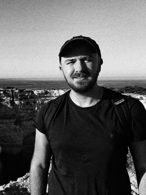 Black and white picture, DR with stubble, wearing black t-shirt and black cap